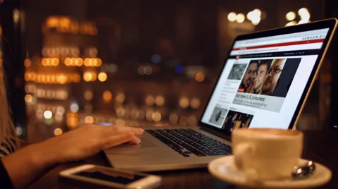 Girl sits in a cafe reading the news on a laptop talking on the phone.  Stock Footage 59276537