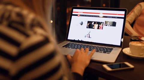 Girl sits in a cafe reading the news cnn on a laptop. Video stock 59288858