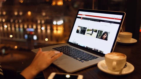 Girl sits in a cafe reading the news on a laptop talking on the phone. Stock Footage 59290560