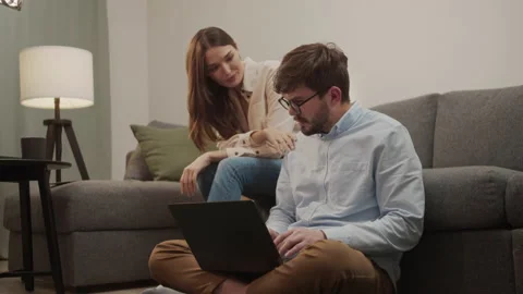 The girl sits down next to the guy and the guy shows her something in the laptop Stock Footage 154913988