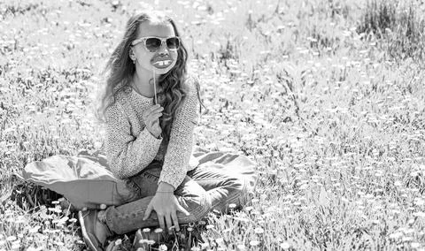 Girl sits on grass at grassplot, green background. Child posing with eyeglasses Stock Photos