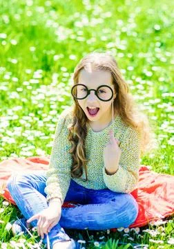 Girl sits on grass at grassplot, green background. Child posing with cardboard Stock Photos