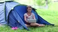 Girl sits on green grass near tourist tent and looks in tablet computer HD Footage