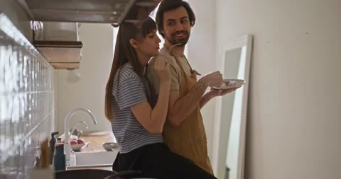Girl sits on kitchen table and hugs her boyfriend while having breakfast with Stock Footage 318079543