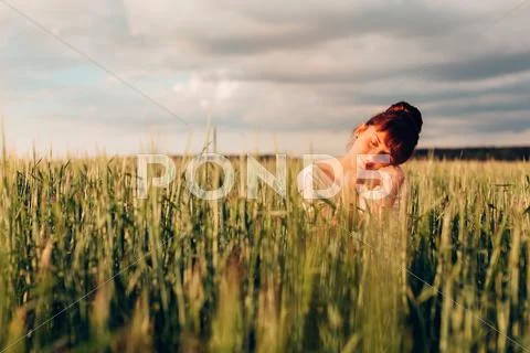 Girl sits in a meadow Stock Photos