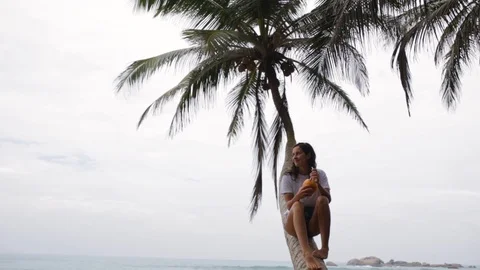 The girl sits on a palm tree Stock Footage 87780437