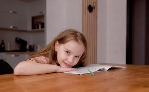 The girl sits at the table and solves problems, does her homework. School theme 写真素材