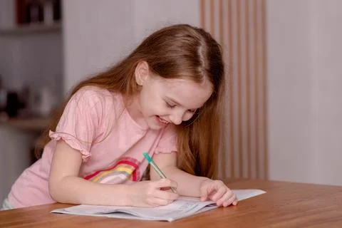 The girl sits at the table and solves problems, does her homework. School theme 写真素材