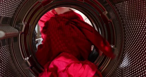 Girl sits at the washing machine and loads dirty laundry at home. View from t Stock Footage