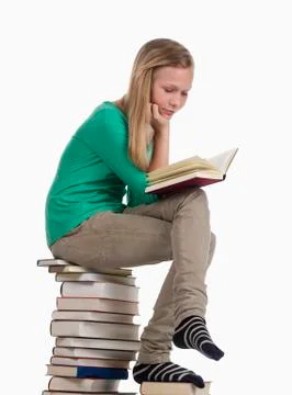 Girl sitting and reading on stack of books against white background 스톡 사진