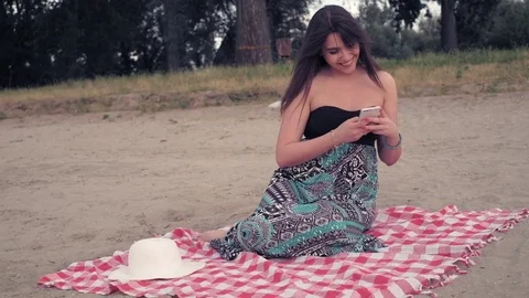 Girl sitting on the beach, using mobile phone and laughing Stock Footage 78120340