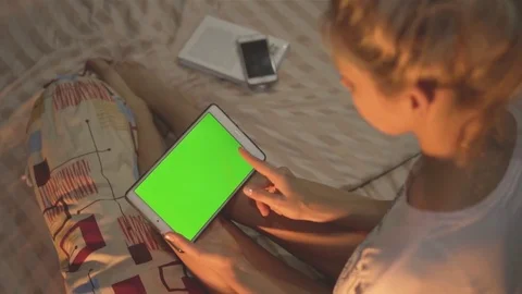 A girl sitting on the bed and using a tablet with chroma key screen. Swiping. Stock Footage 83672305