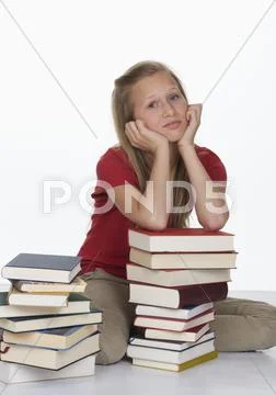 Girl sitting besides stack of books against white background Stock Photos