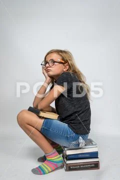 Girl Sitting on Books Thinking Stock Photos
