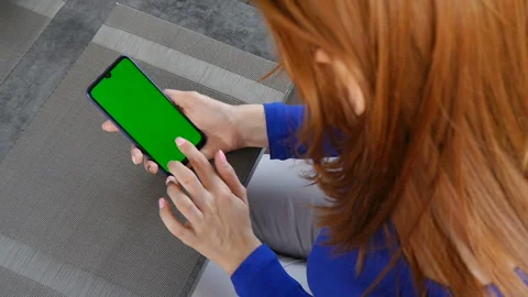 Girl sitting in a cafe and using mobile phone with green screen. Close up. Stock Footage 110749727