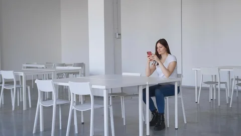 Girl sitting in an empty white audience, straightens her hair and smiling. Stock Footage 126628672