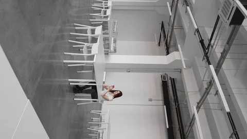 Girl sitting in an empty white audience, straightens her hair and smiling. Stock Footage 126748767