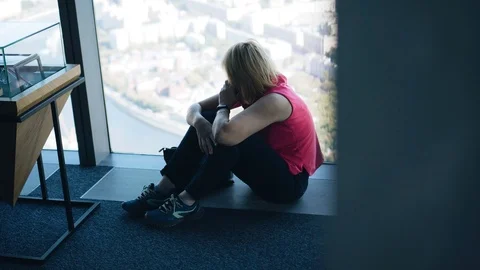 The girl is sitting on the floor in front of a large window in a skyscraper Stock Footage 115259656