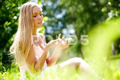 A girl sitting on grass and applying hand cream Stock Photos