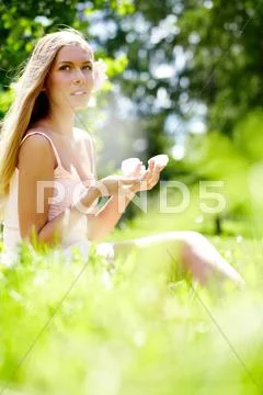 A girl sitting on grass with hand cream Stock Photos