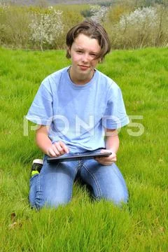 Girl sitting on the lawn and using digital tablet Stock Photos