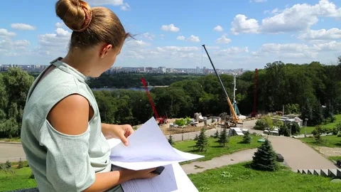 A girl is sitting on a step looking at a construction project. Stock Footage 97267705