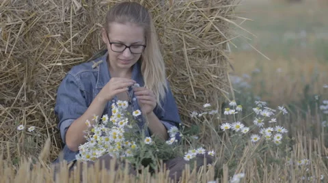 Girl sitting in the straw stack and guesses on camomile Video stock 67376339