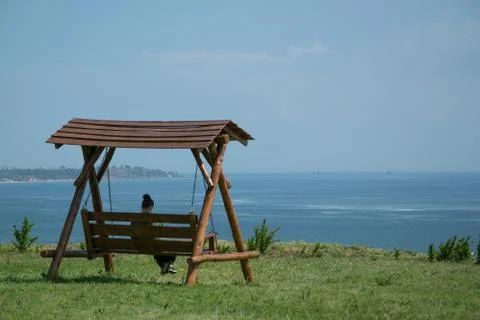 Girl sitting on a swing with a sea view Stock Photos