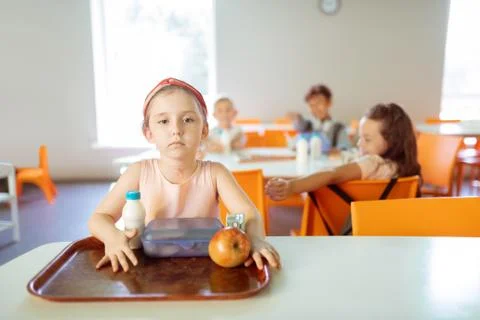 Girl sitting at the table alone while suffering from mockery Foto stock