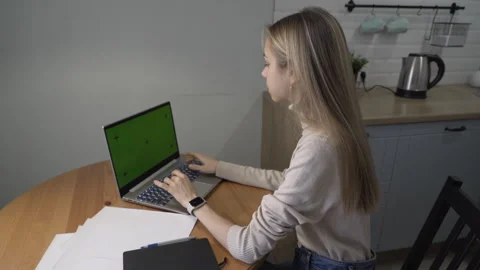 Girl sitting at table in kitchen working on laptop Stock Footage 260875278