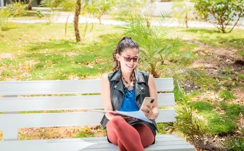 A girl sitting taking notes with a notebook and cell phone, Woman sitting t.. Stock Photos