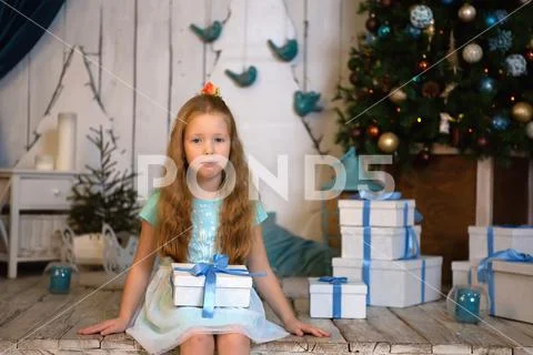 Girl sitting on the wooden floor in a mint dress. holding a gift. Stock Photos