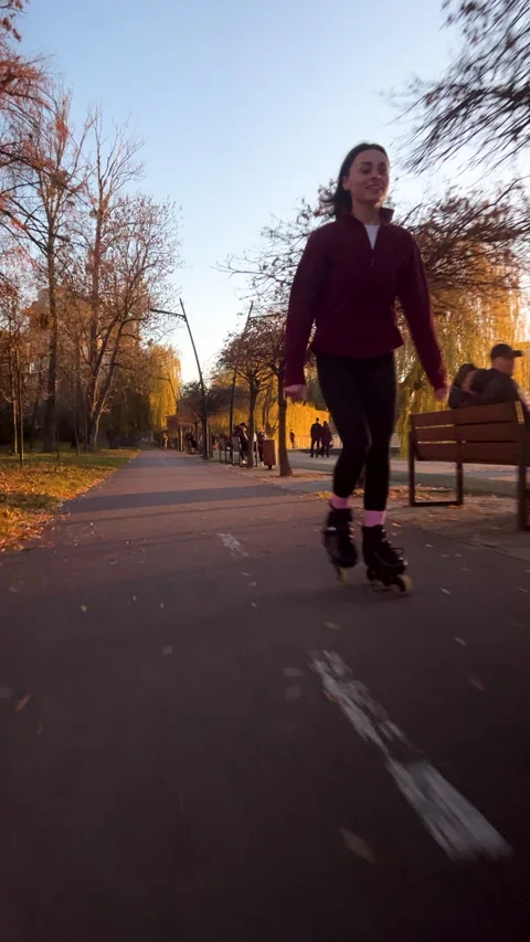 Girl skates on inline skates during sunset in open city space. Vertical shot Stock Footage 346546396