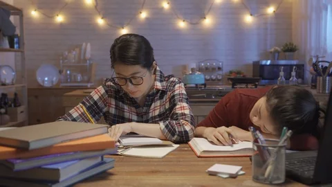 Girl sleep on table while another doing homework Stock Footage 104900104