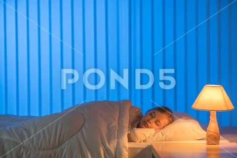 The girl sleeping on the bed. Evening night time Stock Photos