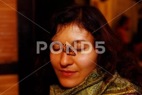 Girl with a small orange butterfly sitting on her face. Stock Photos