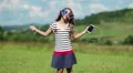 Girl with smartphone stands on meadow, listens to music, dances and sings a song HD Footage