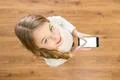 The girl smile to camera and hold a phone in hands. View from above Photo