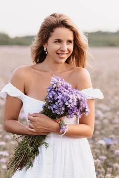 Girl smiles in a white dress with a bouquet of flowers Stock Photos