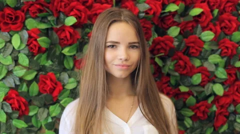 Girl smiling at camera on the background of red roses Stock Footage 67860287