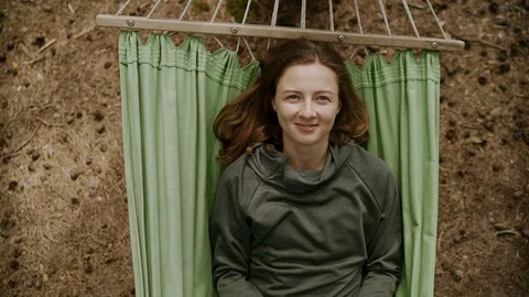Girl smiling to the camera while reading book on hammock in forest Stock Footage 112107409