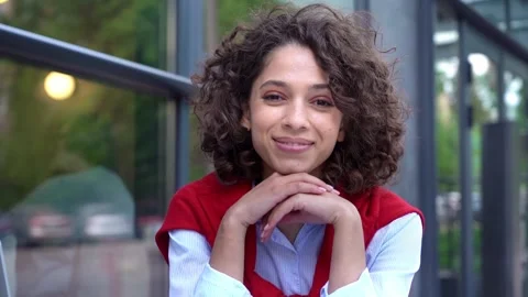 Girl smiling at the camera while sitting at a table in a cafe, slow motion 库存影片 167334429