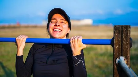 Girl smiling doing pullups Stock Photos