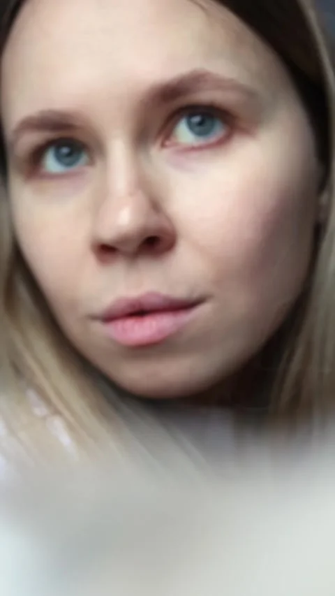 A girl smiling while applying blush to her cheeks with a fluffy brush Stock Footage 299894509