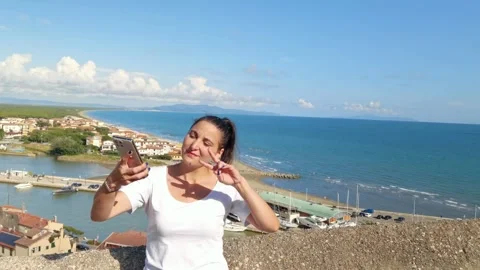 A girl smiling while taking a selfie with her smartphone with a panoramic view Stock Footage 251764266