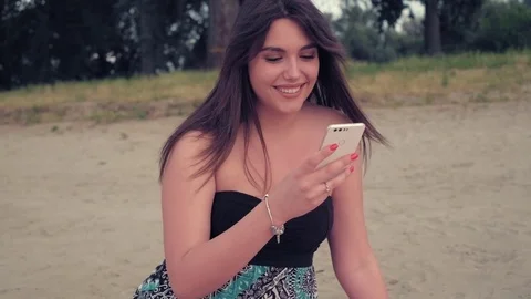 Girl smiling while using phone on the beach Stock Footage 78120236