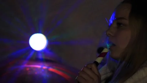A girl smokes a hookah in the dark under the light of a multi-colored lamp. Stock Footage 128417341
