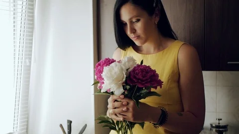 Girl sniffs flowers. A beautiful white girl brings a bouquet of peonies to her Stock-Footage 111571653