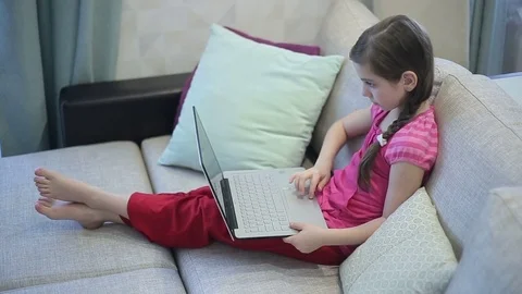 A girl on the sofa is educating herself on a laptop Stock Footage 73358949