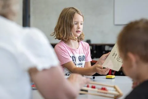 A girl is solving a math problem on a white board. Stock Photos